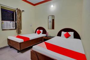 um quarto com 2 camas com lençóis vermelhos e brancos em OYO Flagship 81231 Urmila Guest House em Bodh Gaya