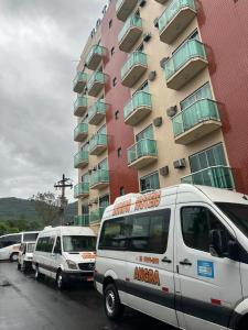 um grupo de carrinhas estacionadas em frente a um edifício em LUXOR VEROLME HOTEL em Angra dos Reis