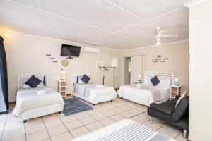 een woonkamer met 2 bedden en een bank bij Gastehuis 17 in Bloemfontein