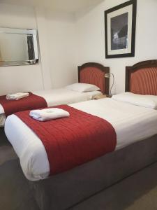 2 letti in una camera d'albergo con coperte rosse e bianche di The Melville Hotel - Central Location a Blackpool