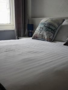 uma cama branca com uma almofada e uma janela em The Melville Hotel - Central Location em Blackpool