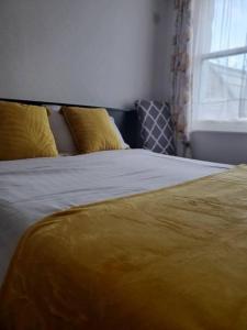 a bed with a yellow blanket and a window at The Melville Hotel - Central Location in Blackpool