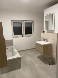 ein Badezimmer mit einem Waschbecken, einer Badewanne und einem Spiegel in der Unterkunft Komfort Deluxe am Airport Weeze in Weeze