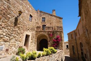 an old stone building with flowers in a courtyard at Casa Rufina, Exclusive & Charming Stone House in Costa Brava in Pals