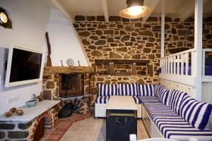 a living room with couches and a stone wall at Aspros Pyrgos in Volissos