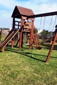 un parque infantil con columpios de madera en el césped en Casa de campo en la Paloma, en Costa Azul