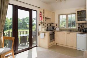 a kitchen with wooden cabinets and a balcony with a table at Blackthorn is a luxurious, rural retreat for two. in Icklesham