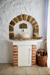 a bathroom with a brick fireplace with a sink at Aspros Pyrgos in Volissos