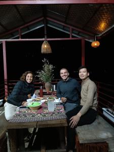 eine Gruppe von Menschen, die an einem Tisch sitzen in der Unterkunft Moc's House in Bắc Hà