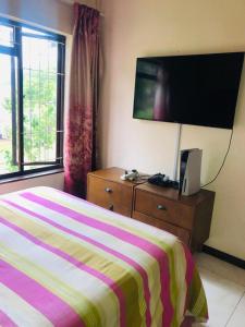 ein Hotelzimmer mit einem Bett und einem Flachbild-TV in der Unterkunft Margate Accomodation in Margate