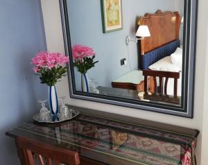 La Collina since 2008 NO SMOKING B&B في فاريزي: مرآة على طاولة مع الزهور في غرفة