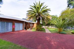 a house with a palm tree and a brick driveway at Gastehuis 17 in Bloemfontein