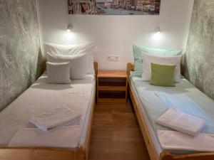 two twin beds in a small room with a table at Tünde Vendégház in Tiszakécske
