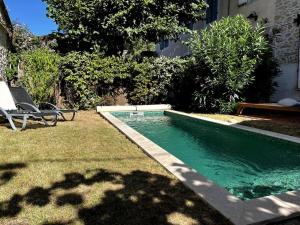 una piscina en un patio con una silla al lado en Maison de Charme Piscine & Piano, 30 min Toulouse, en Loubens-Lauragais