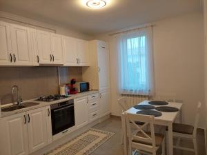 a kitchen with white cabinets and a table and a sink at Trandafirului Residence Central Suceava in Suceava