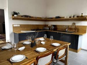 einen Holztisch mit Tellern und Weingläsern darauf in der Unterkunft Maison de Charme Piscine & Piano, 30 min Toulouse in Loubens-Lauragais