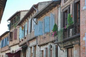 un edificio con persianas azules y balcones en una calle en Maison de Charme Piscine & Piano, 30 min Toulouse en Loubens-Lauragais