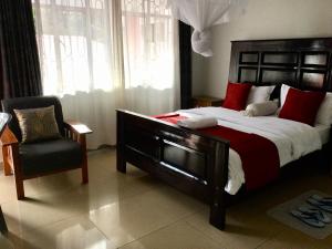 1 dormitorio con 1 cama grande y 1 silla en Milimani Comfort, en Kisumu