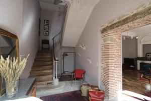 ein Wohnzimmer mit einer Treppe und einem roten Stuhl in der Unterkunft Maison de Charme Piscine & Piano, 30 min Toulouse in Loubens-Lauragais