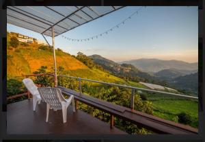 a balcony with two chairs and a view of a mountain at ฮักวิว ม่อนแจ่ม in Mon Jam
