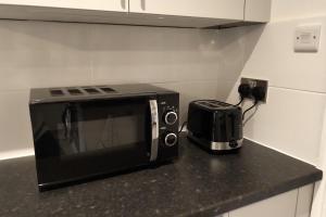 eine Mikrowelle auf einer Theke neben einem Toaster in der Unterkunft Oliver Wests Beautiful 2 Bedroom Sleeps 4 Apartment in Scarborough