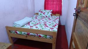 ein kleines Bett in einem kleinen Zimmer mit einer Bettdecke mit Blumen in der Unterkunft SCENIC HOMESTAY in Cherrapunji