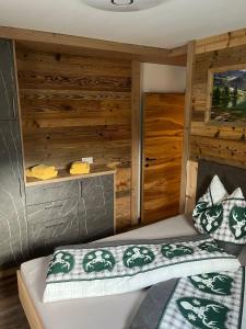 Bett in einem Zimmer mit Holzwänden in der Unterkunft Ferienwohnung Sabine in Flattach
