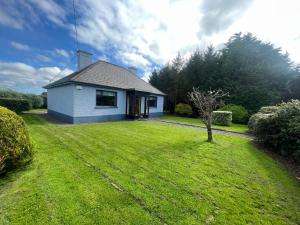 uma pequena casa branca com um jardim de relva em An Cnoc em Killorglin