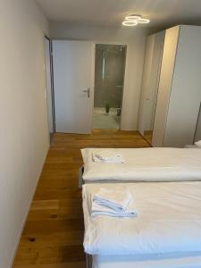 um quarto com duas camas com lençóis brancos e um corredor em Modern City Apartment em Interlaken