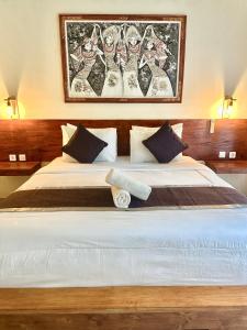 een slaapkamer met een groot wit bed met een foto aan de muur bij The Dulu Penida Cottage in Nusa Penida