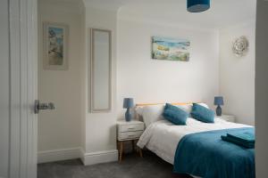 a white bedroom with a bed and a mirror at Large newly refurbished modern house, part sea views, south facing garden, parking in Penzance