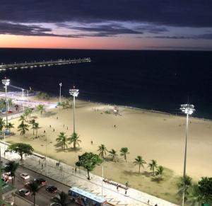 una playa con palmeras y el océano por la noche en Apto Terraços do Atlântico, en Fortaleza