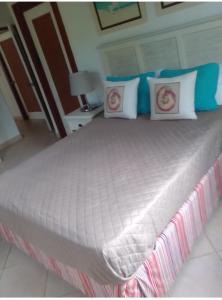Una cama grande con almohadas azules y blancas. en Villa Mares en Playa Bonita ,coson Las Terrenas, en Cosón