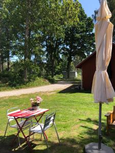 einen Tisch, Stühle und einen Regenschirm im Hof in der Unterkunft Agundaborg boathouse close by lake in Agunnaryd