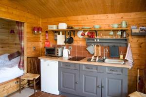 a kitchen with a counter and a bed in a room at Cedarwood, an intimate and romantic cabin for two. in Icklesham