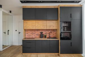 a kitchen with black cabinets and a brick wall at Koźla Warsaw Old Town 1-Bedroom Superior Apartment WWA54 in Warsaw