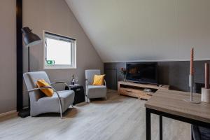 ein Wohnzimmer mit zwei Stühlen und einem Fernseher in der Unterkunft Het Waterhoentje in Sint Jansklooster