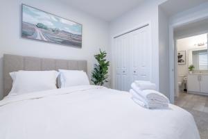 カルガリーにあるStylish Getaway 2BD Basement by YMCA and South Health Campus Hospitalの白いベッドルーム(白い枕の大きな白いベッド付)