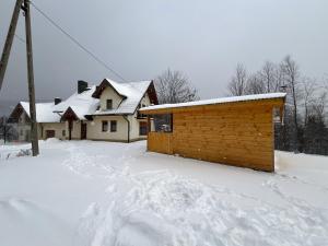 una casa con nieve en el suelo delante en Domek na Stasince, en Sidzina