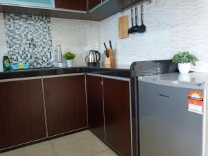 cocina con armarios marrones y nevera en [Georgetown] 2~6 Pax, 3 Bedrooms, 1 Car Park, en Jelutong