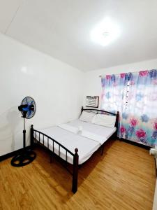 um pequeno quarto com uma cama e uma ventoinha em Calapan Transient Molave L48 em Calapan