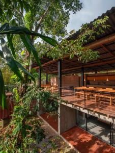 una terrazza in legno con tavoli e panche sotto un pergolato in legno di River Pavilion, Kitulgala a Yatiyantota