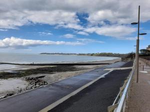 una carretera junto a una playa con el océano en Petit bijou à Saint Pair sur Mer en Saint-Pair-sur-Mer
