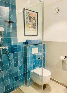 y baño de azulejos azules con aseo y ducha. en Traumhafte Ferienwohnung in historischem Brandmanngut en Marquartstein