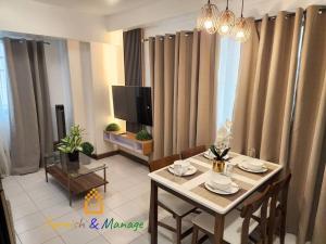 a living room with a table with chairs and a television at 3 Bedroom Corner Panoramic View in Davao City