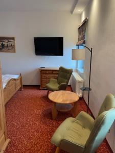 クアオルト・オーバーヴィーゼンタールにあるNeues Haus - Berggasthof und Hotelの椅子2脚、テーブル、テレビが備わる客室です。