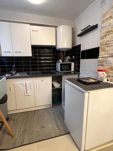 a kitchen with white cabinets and black tiles at Appartement à 10 minutes du Stade de France in Saint-Denis