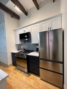 a kitchen with a stainless steel refrigerator and white cabinets at Chic Two-Bedroom Apartment on Camp St, New Orleans in New Orleans