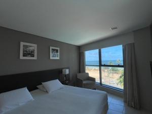 a hotel room with a bed and a large window at BEACH CLASS INTERNACIONAL FRENTE MAR in Recife
