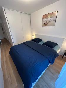 a bedroom with a blue bed with two pillows at Ideal family flat in st-ouen in Saint-Ouen